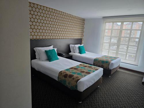 a hotel room with two beds and a window at Hotel Castellana 95 Bogota By Hoteles Confort 80 in Bogotá
