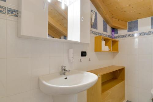 W łazience znajduje się biała umywalka i lustro. w obiekcie Roe Apartment w mieście Panchia