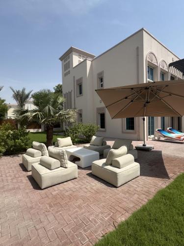 a group of couches and an umbrella on a patio at Family Villa, Sleeps up to 9 in JVT and Large garden in Dubai