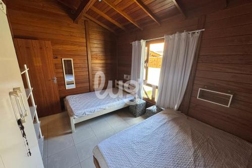 Casa Aconchegante – A 200m da praia da Pinheira في بينيرا: غرفة نوم بسريرين في غرفة خشبية