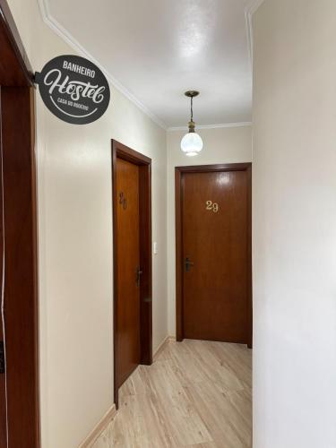 a hallway with two doors and a sign on the wall at Casa do Rogerio Hostel - Unidade Shopping in Caxias do Sul
