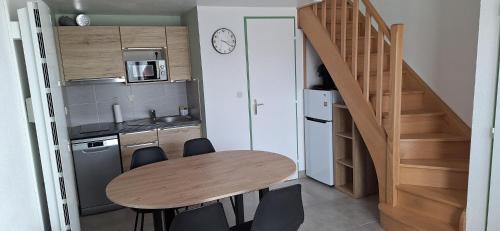 a small kitchen with a wooden table and a staircase at Domaine in Saint-Hilaire-de-Riez