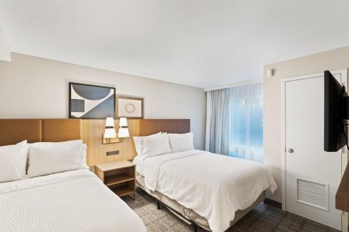 a hotel room with two beds and a flat screen tv at Staybridge Suites North Brunswick by IHG in North Brunswick
