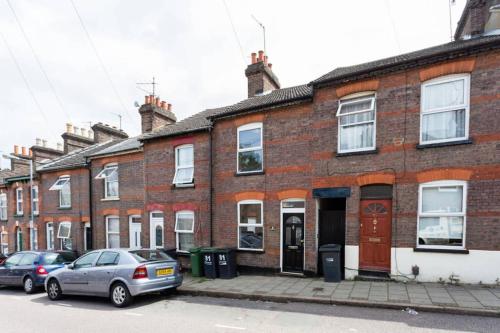 a row of brick houses with cars parked in front at Ashton House - Stylish 2 Bedroom House, Close to Luton Town Center & Airport in Luton