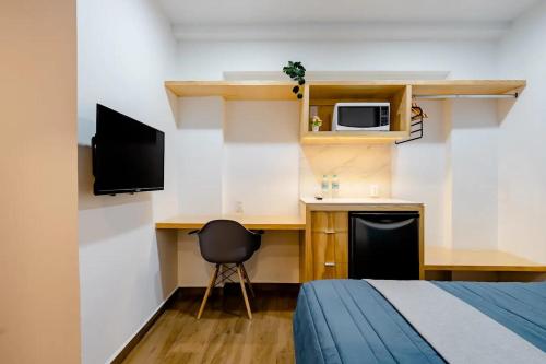 a room with a bed and a desk with a microwave at Aloja Rentals Mexico in Mexico City