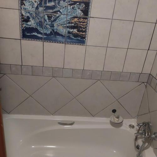 a bathroom with a white tub and a tile wall at Glenmore Sea View in Leisure Crest