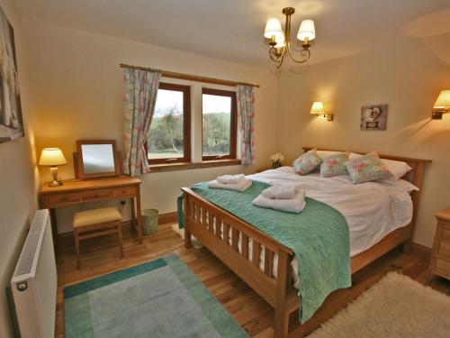 a bedroom with a bed and a desk and a window at Laggansally Lodge in Leswalt