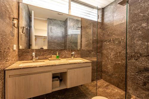 Un baño con lavabo y ducha de cristal. en Stunning Sea Views from 3BR Penthouse F3, en Pendales