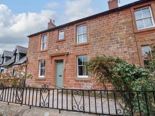 a brick house with a black iron fence at Milford in Great Corby