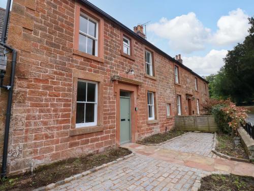 a brick building with a door and a courtyard at Milford in Great Corby