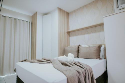 a bedroom with a white bed with a blanket on it at Apto Aconchegante em Jardim Camburi in Camburi