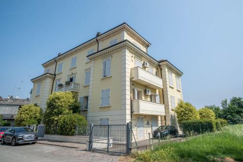 a large yellow building with cars parked in front of it at Il Castello - Appartamento in zona residenziale in Modena