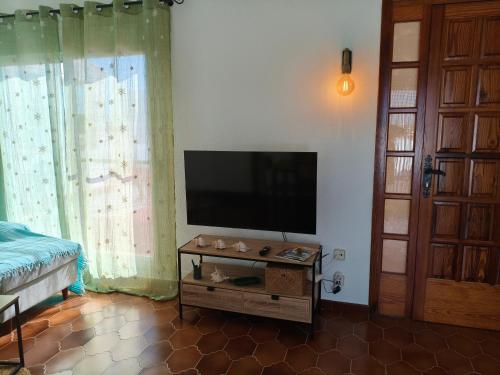a living room with a flat screen tv and a table at L'àtic dels flamencs in Sant Jaume d'Enveja