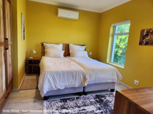 ein Schlafzimmer mit einem Bett mit gelben Wänden und einem Fenster in der Unterkunft Suite Shiraz in Meadowridge