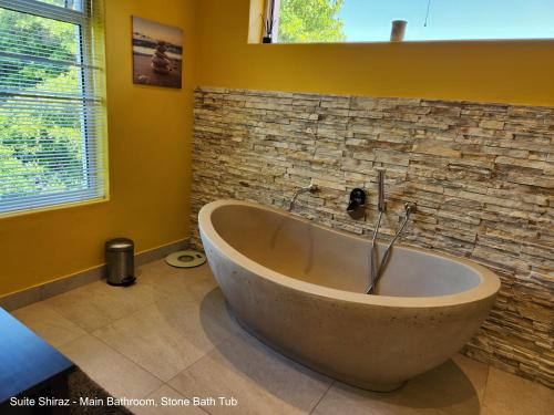 eine Badewanne im Bad mit einer Steinmauer in der Unterkunft Suite Shiraz in Meadowridge
