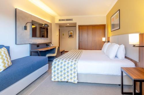 a hotel room with a bed and a desk at Holiday Inn Algarve Albufeira by IHG in Albufeira
