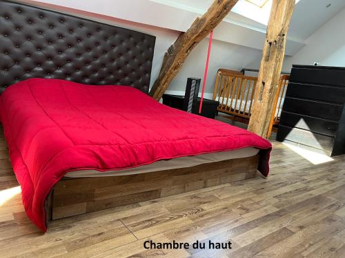 a bed with a red blanket on top of it at La maison de Maxou in Briare