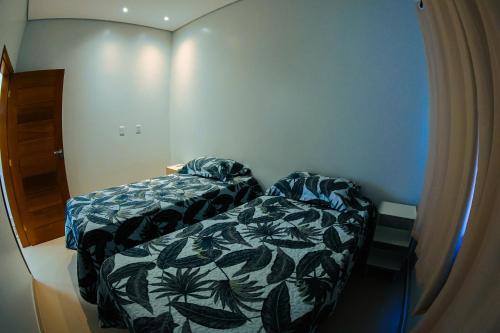 une petite chambre avec un lit et un couvre-lit avec des feuilles dans l'établissement Conforto em Boa Vista com varanda e garagem privado, à Boa Vista