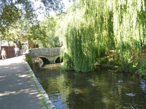 a bridge over a river with ducks in the water at Coastal Calm at Stanpit Hideaway in Christchurch