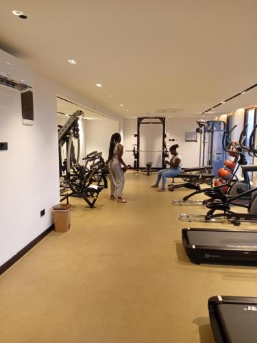 a woman standing in a gym with tread machines at Real Homes 2 bedroom Nova Apartments in Accra