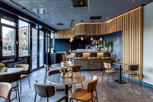 a restaurant with tables and chairs and a bar at NH Noordwijk Conference Centre Leeuwenhorst in Noordwijkerhout