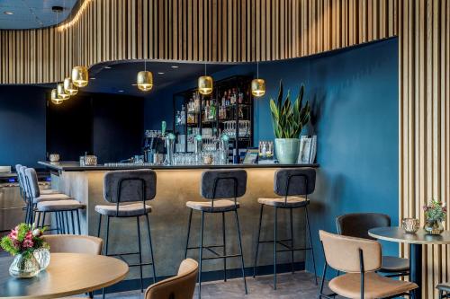 a bar in a restaurant with blue walls and stools at NH Noordwijk Conference Centre Leeuwenhorst in Noordwijkerhout