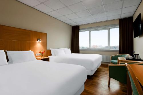 a hotel room with two beds and a desk at NH Noordwijk Conference Centre Leeuwenhorst in Noordwijkerhout