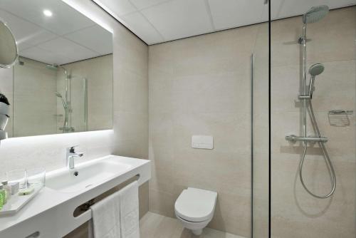 a bathroom with a shower and a toilet and a sink at NH Noordwijk Conference Centre Leeuwenhorst in Noordwijkerhout