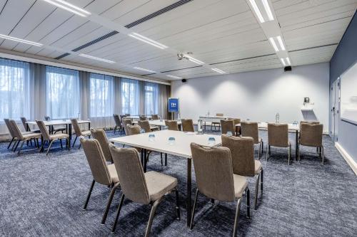a room with tables and chairs in a room at NH Noordwijk Conference Centre Leeuwenhorst in Noordwijkerhout