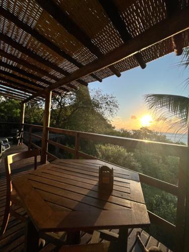 a wooden table on a deck with the sunset in the background at Casa do Ney in Fernando de Noronha