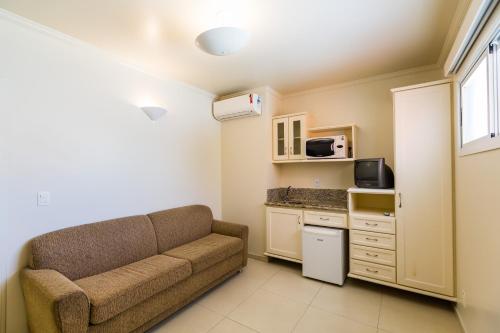 a living room with a couch and a kitchen at Hotel Vila do Farol in Bombinhas