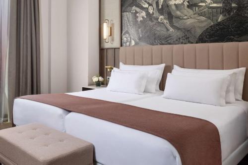 a bedroom with a large bed and a painting at NH Collection Victoria in Granada