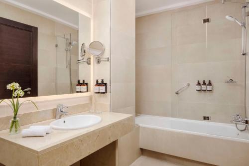 a bathroom with a sink and a tub and a mirror at NH Collection Victoria in Granada