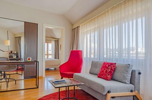 a living room with a couch and a red chair at NH Collection Roma Giustiniano in Rome