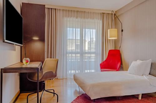 a hotel room with a bed and a red chair at NH Collection Roma Giustiniano in Rome