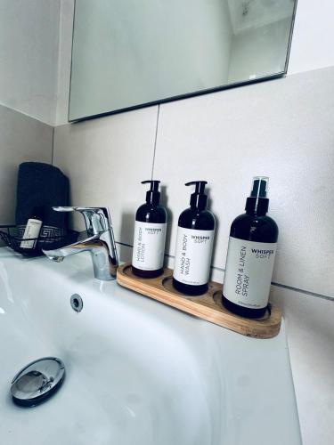 a bathroom sink with three bottles of soap on a shelf at 2Bed in exquisite golf estate! in Roodepoort