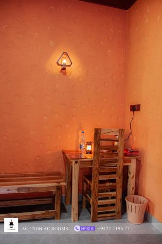 a room with a wooden table and a light on the wall at Sam's Stay Buduruwagala in Wellawaya