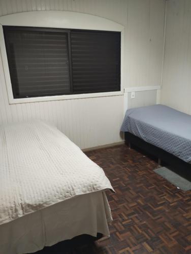 two twin beds in a room with a window at Pousada aeroporto in Chapecó