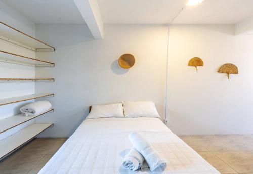 a white bedroom with a bed and shelves at Sapê Guest Hotel in Praia do Rosa