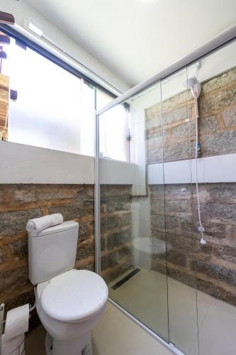 a bathroom with a toilet and a glass shower at Sapê Guest Hotel in Praia do Rosa