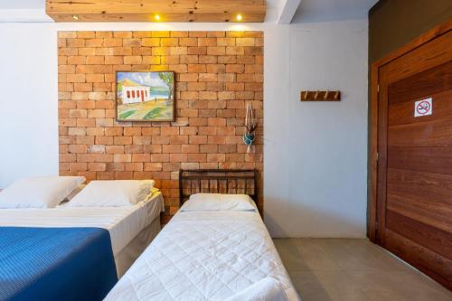 a bedroom with two beds and a brick wall at Sapê Guest Hotel in Praia do Rosa