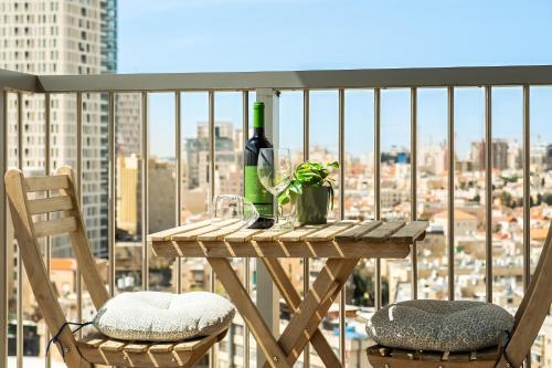 a table with a bottle of wine and two chairs on a balcony at MR savyon view 2BR with balcony in Jerusalem