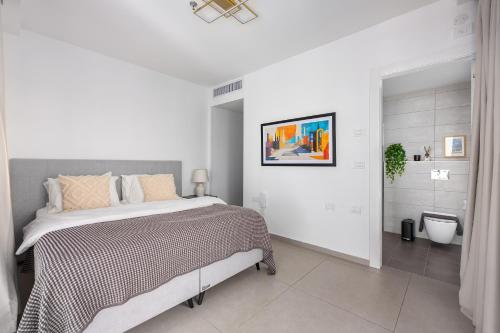 a white bedroom with a bed and a bathroom at MR savyon view 2BR with balcony in Jerusalem