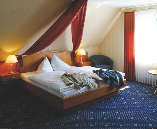 a bed in a hotel room with clothes on it at Zur Linde in Heede