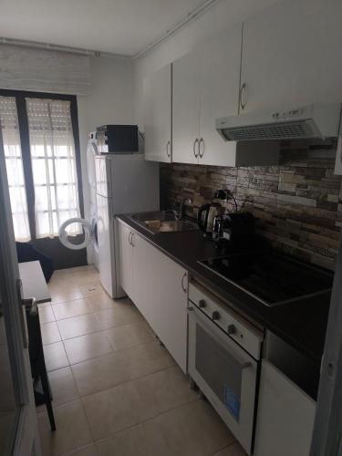 a kitchen with white cabinets and a black counter top at Albergue con encanto d'camiño in Padrón