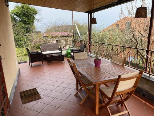eine Terrasse mit einem Holztisch und Stühlen auf dem Balkon in der Unterkunft Ciury's Etna Holidays in Trecastagni