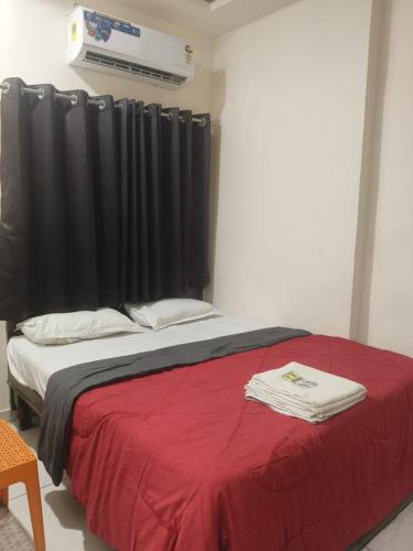 a bed with a red blanket and a black curtain at HOTEL OM VADODARa in Vadodara