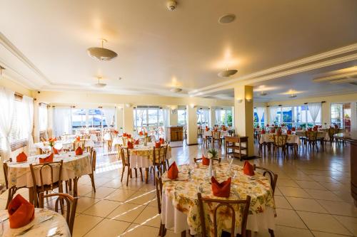 a banquet hall with tables and chairs in a restaurant at Hotel Vila do Farol in Bombinhas