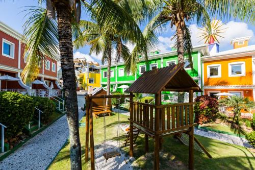 a playground in the courtyard of a resort with palm trees at Hotel Vila do Farol in Bombinhas