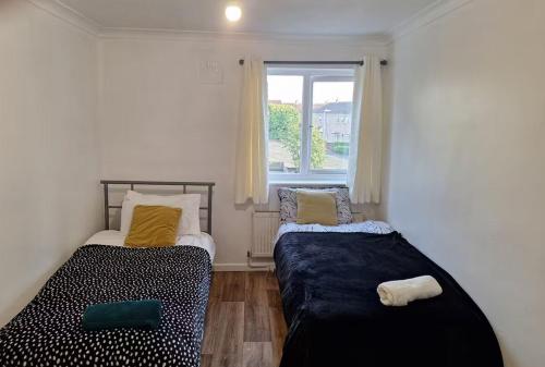 two beds in a small room with a window at Cosy 2BR Retreat in Huntingdon near City Centre in Hartford